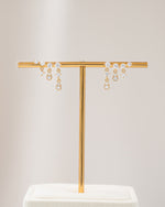 Gold chain earrings with cubic zirconia stone standing on an earring stand