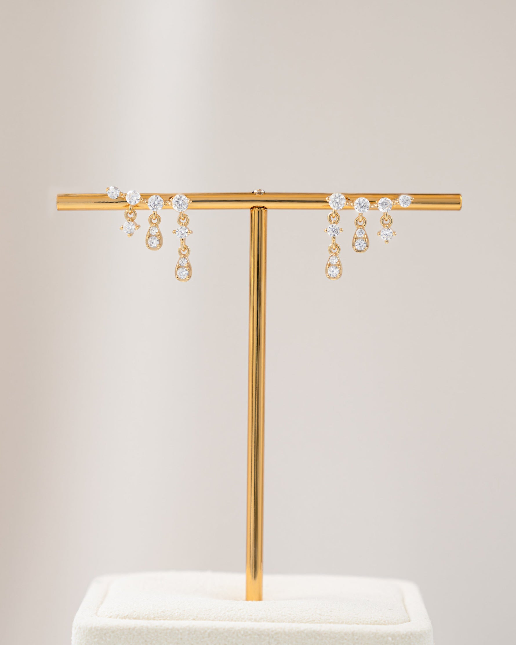 Gold chain earrings with cubic zirconia stone standing on an earring stand
