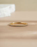 Gold diamond stacking ring on a beige surface