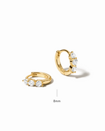 Gold hoop earrings with embedded cubic zirconia stones on a white background