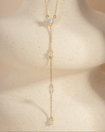 Gold diamond lariat necklace on a beige background 