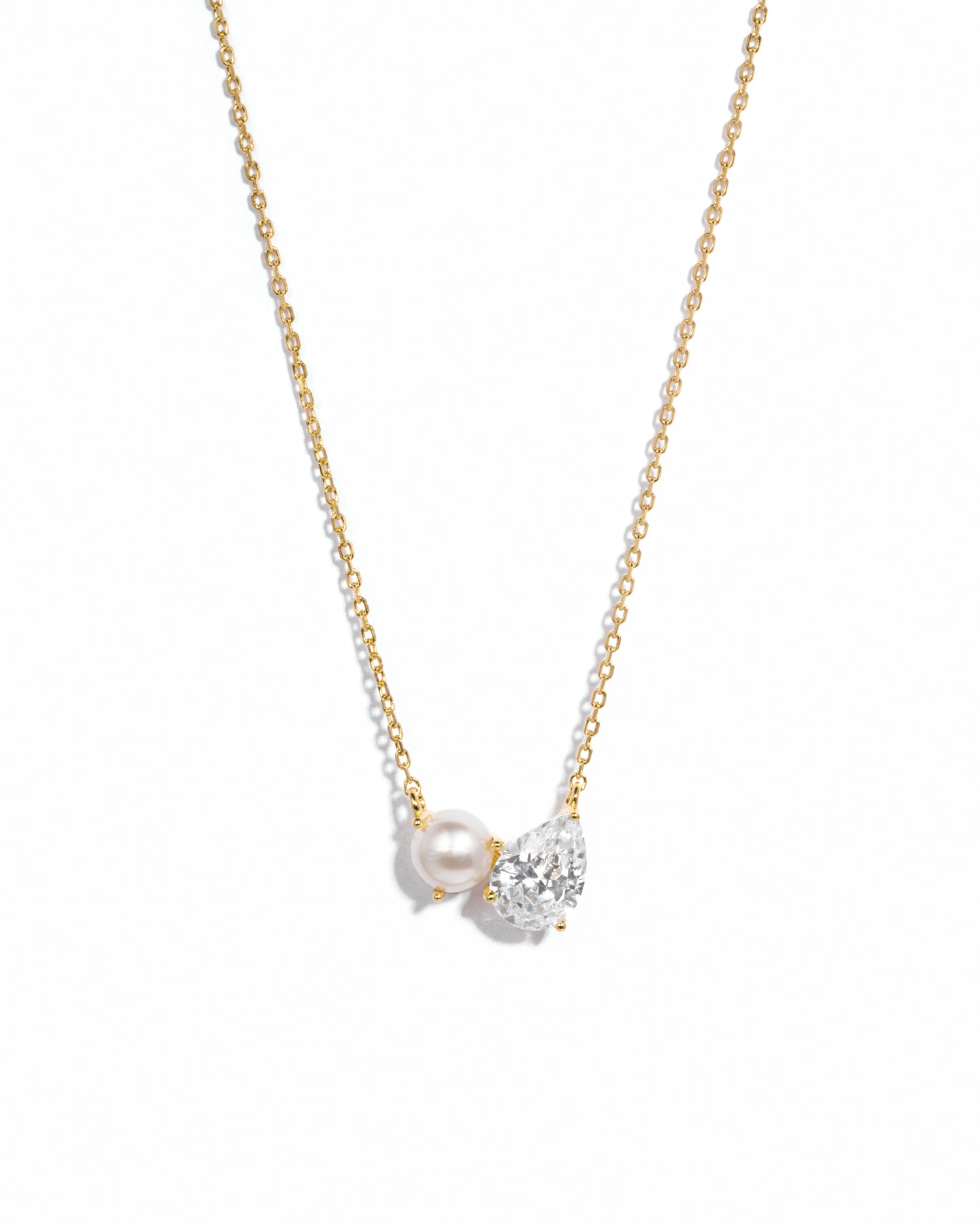 Necklace with a pearl and small diamond pendant on a gold chain against a white background