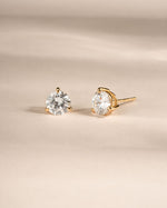 Gold dainty diamond earrings on neutral background