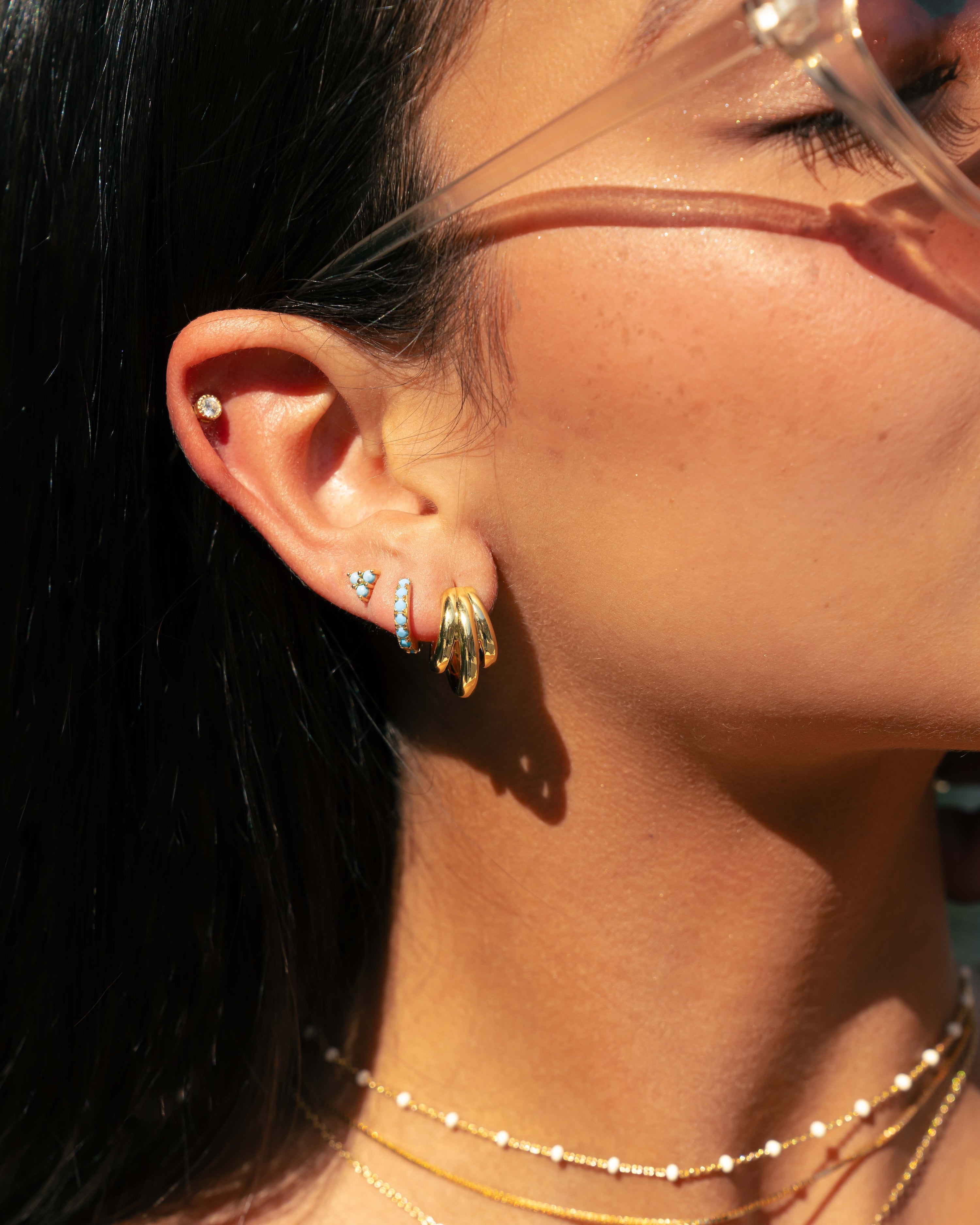 Gold triple hoop earring on model with turquoise earrings
