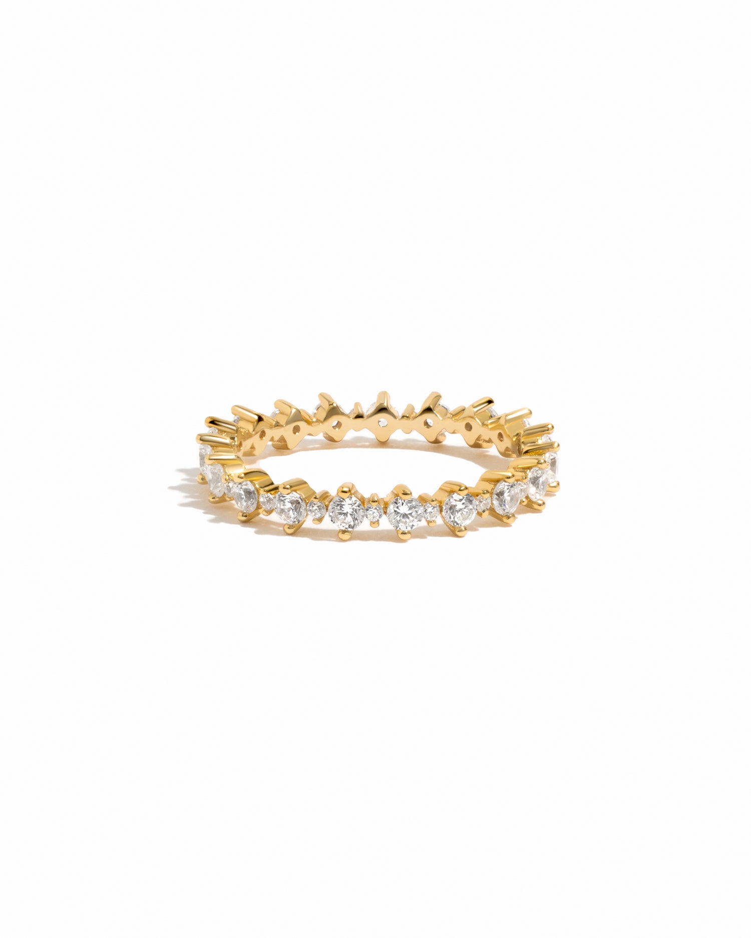 Gold ring with embedded diamonds on a eternity band on a white background