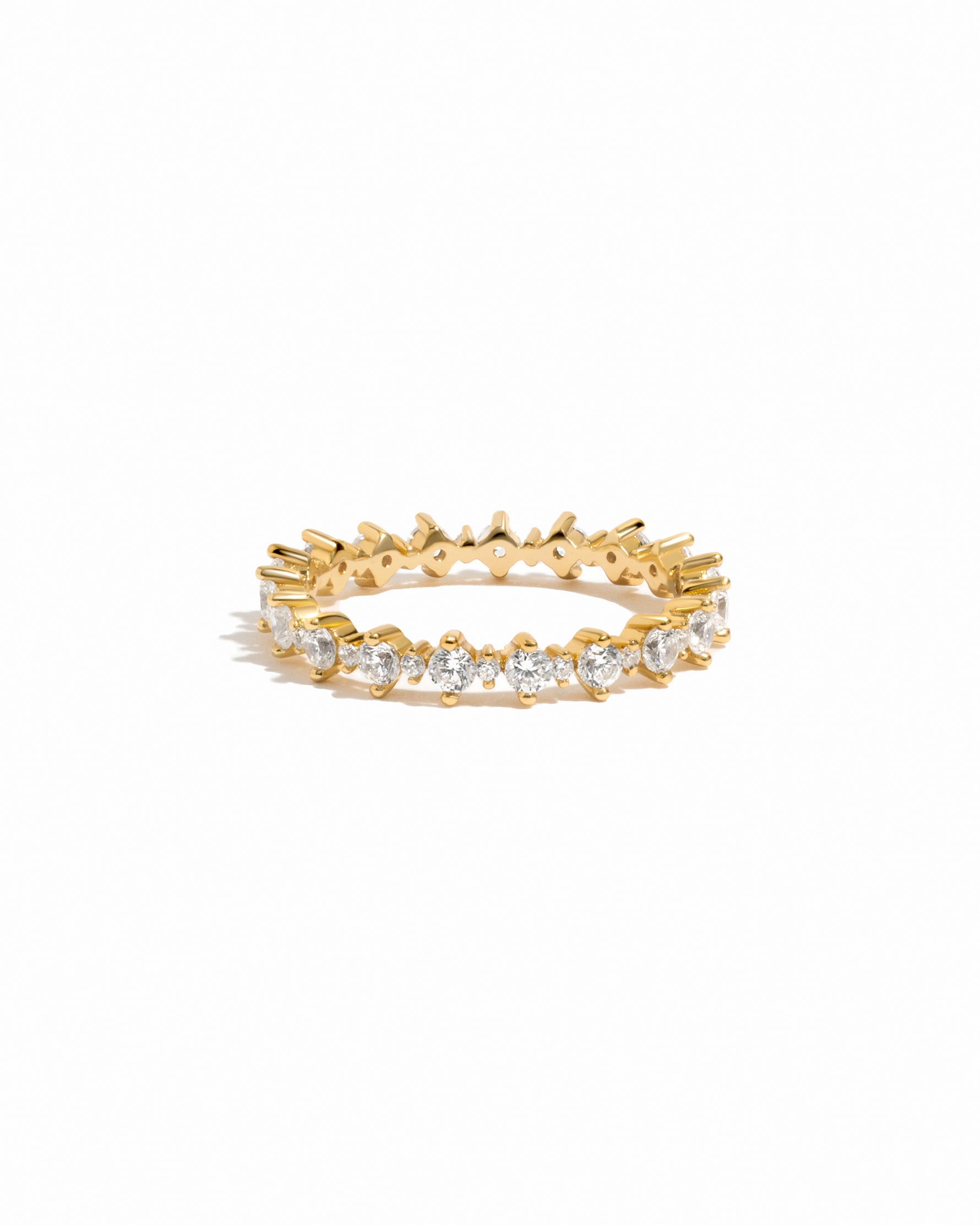 Gold ring with embedded diamonds on a eternity band on a white background