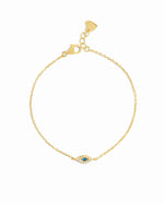 Gold bracelet with a small evil eye charm on a white background