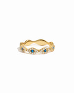 Gold evil eye ring with blue gemstones on a white background