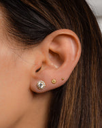 A model's ear with diamond halo and gold tiny flower studs.