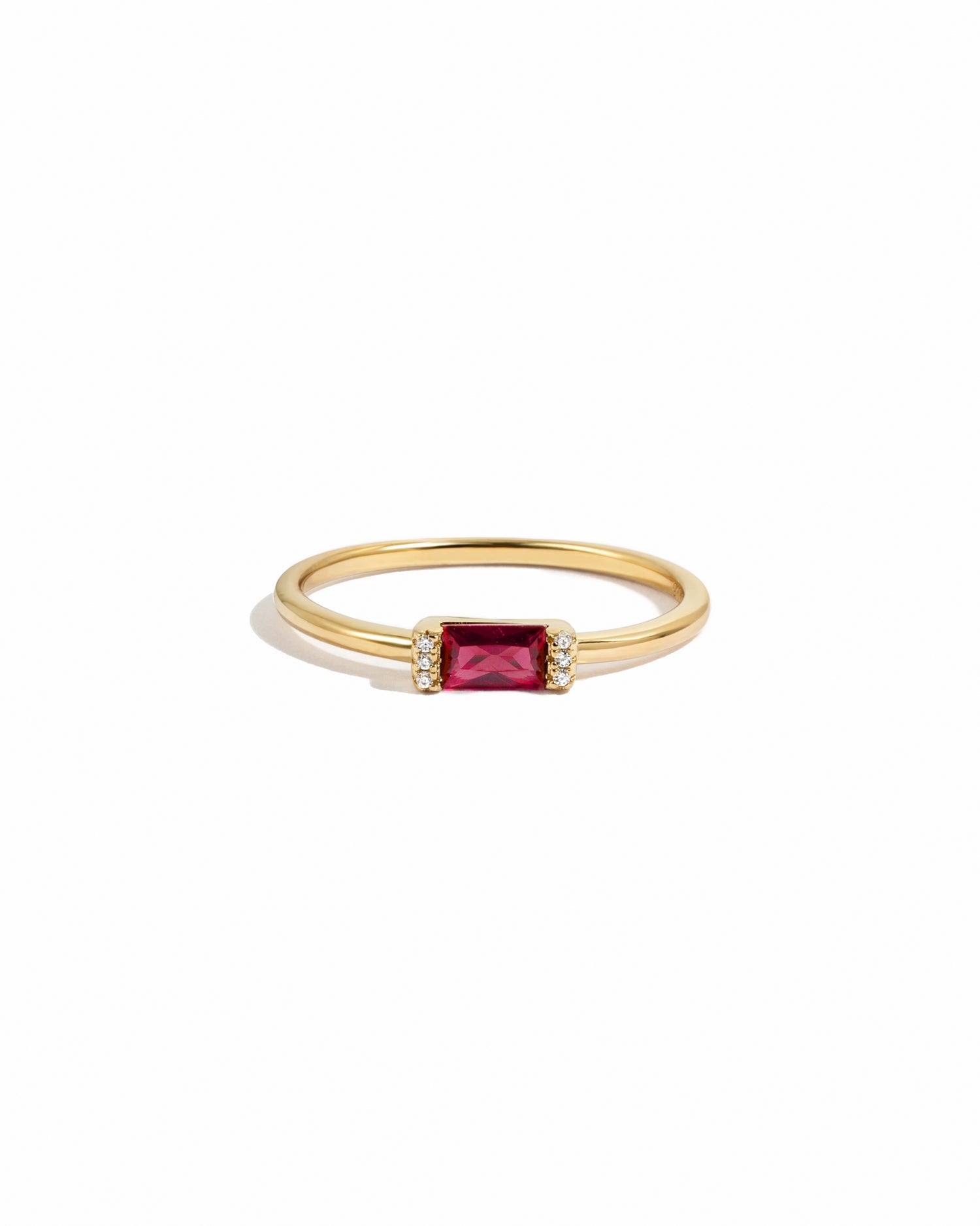 Gold diamond birthstone ring with garnet birthstone on a white background