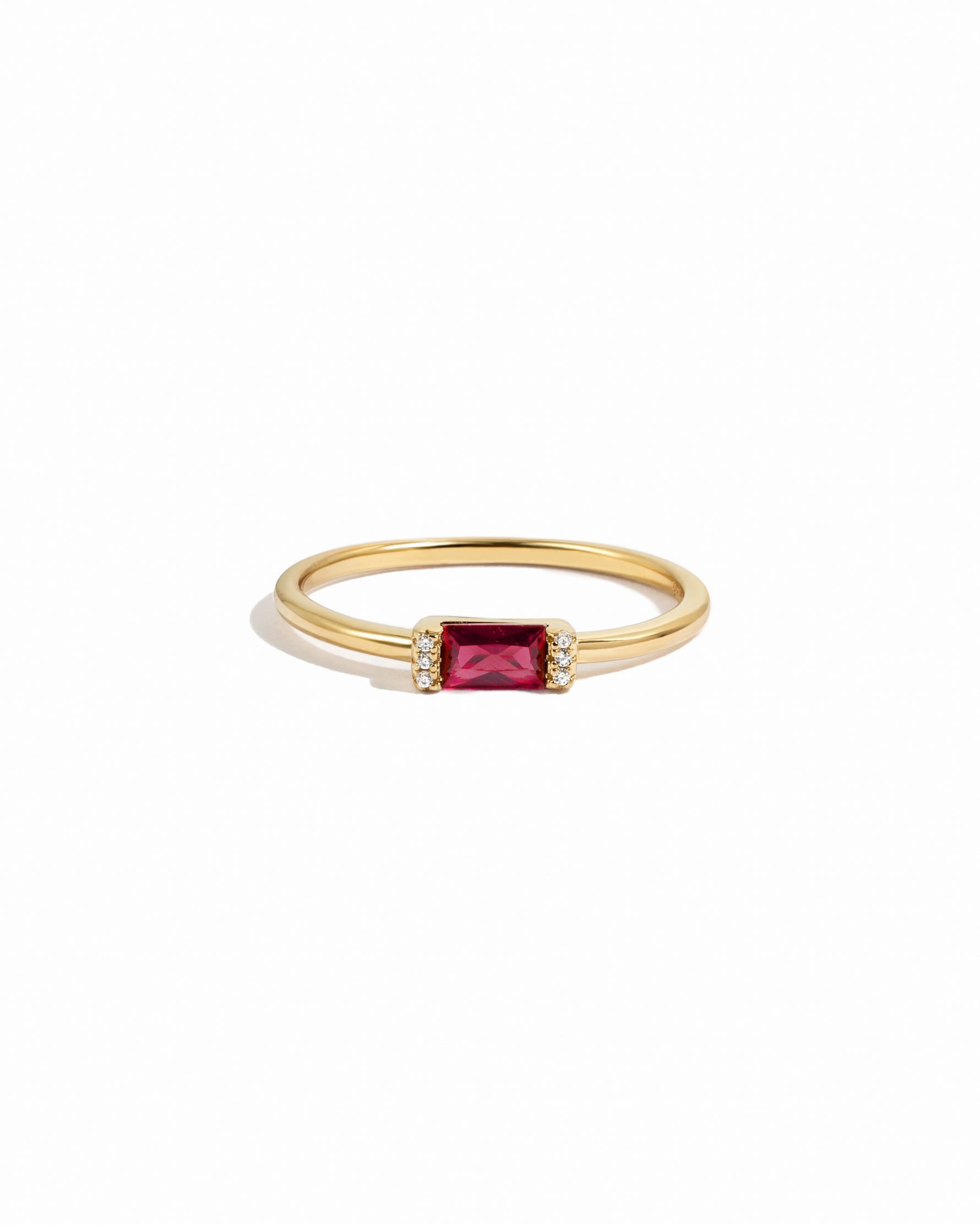 Gold diamond birthstone ring with garnet birthstone on a white background
