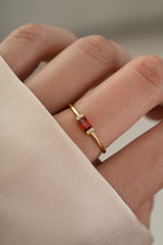 Model wearing simple baguette birthstone ring with a garnet gemstone