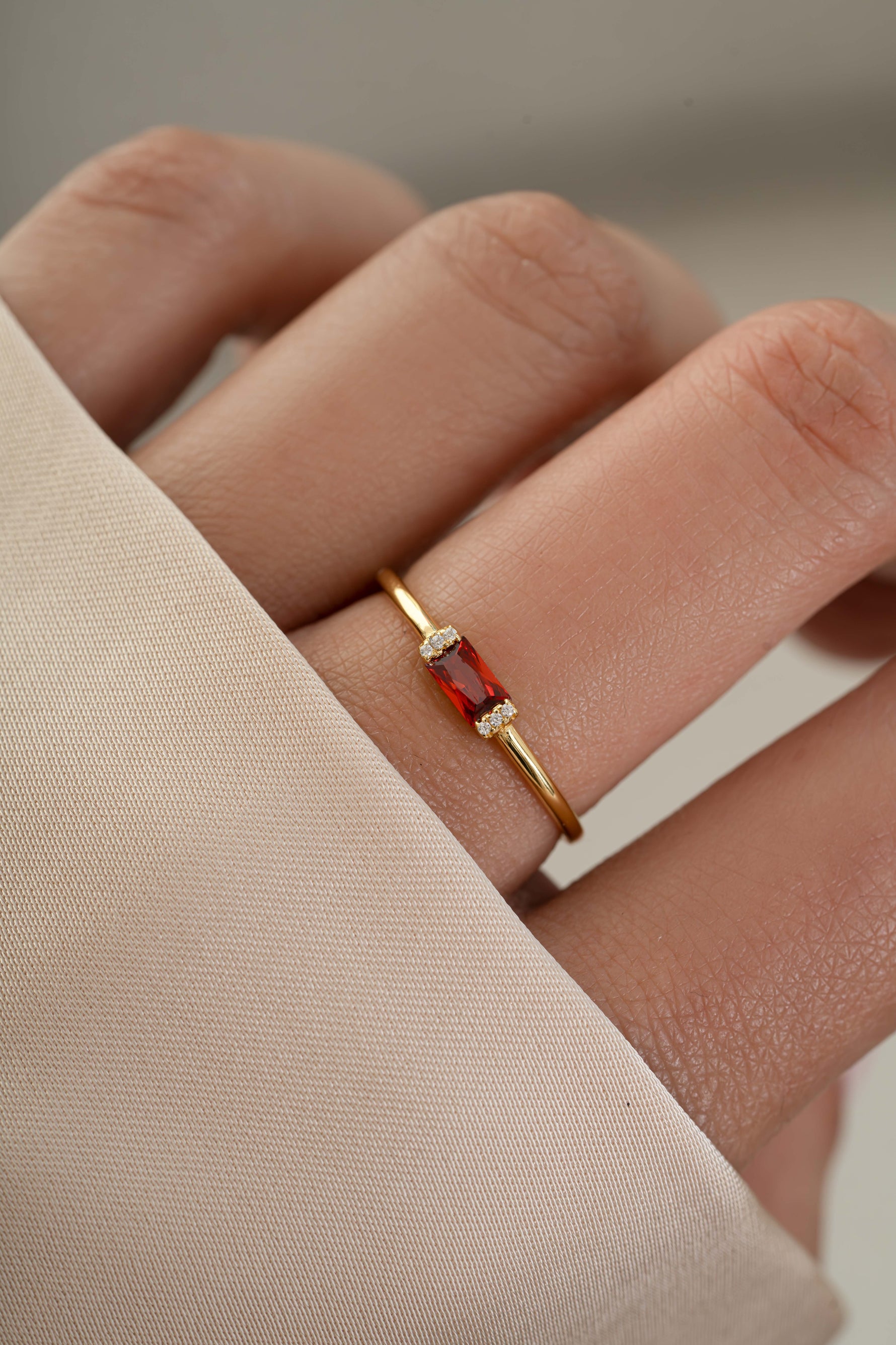 Model wearing simple baguette birthstone ring with a garnet gemstone