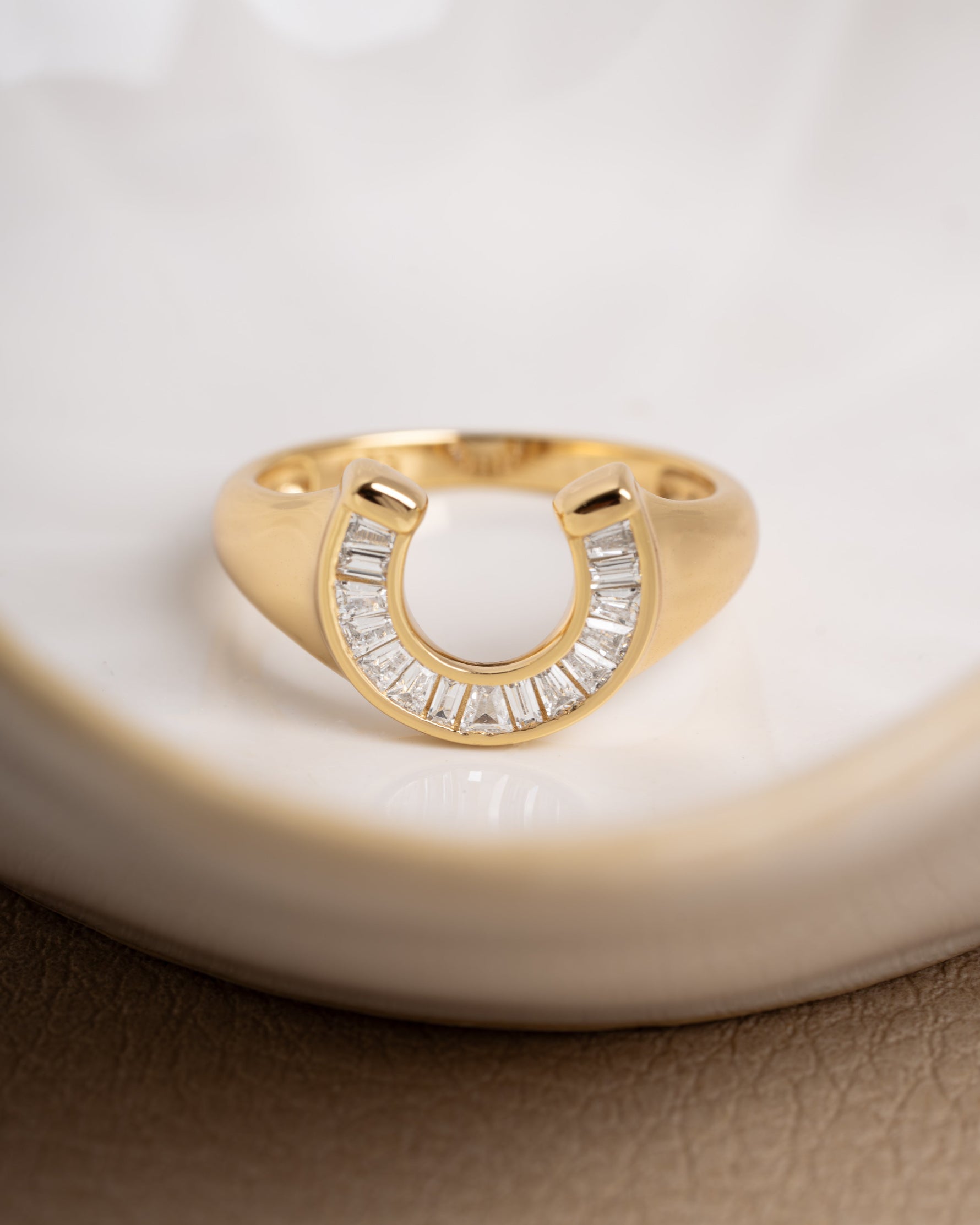 Gold baguette ring with a signet ring design on a decorative plate