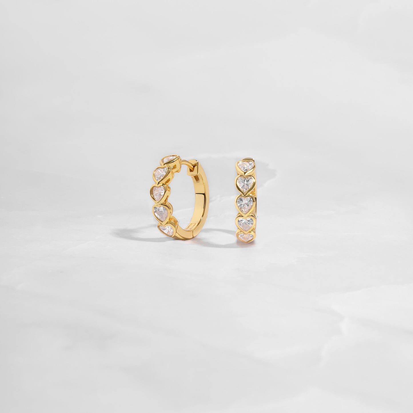 Delicate heart hoop earrings featuring a polished gold finish, great for stacking or wearing solo as a statement piece. 