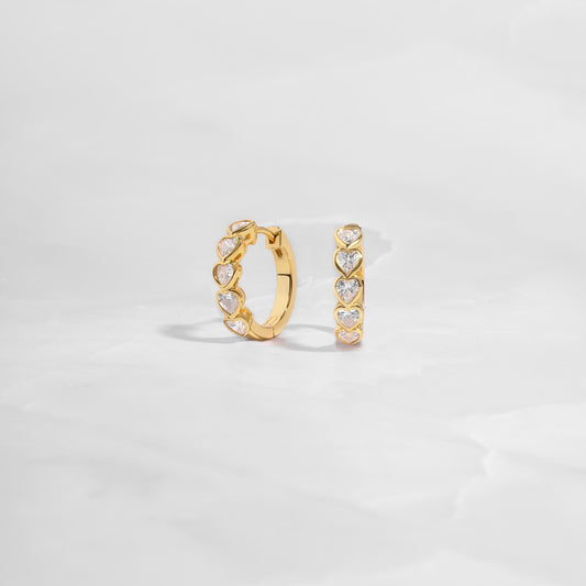 Delicate heart hoop earrings featuring a polished gold finish, great for stacking or wearing solo as a statement piece. 