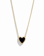 Close-up of a heart necklace with black onyx, set on a delicate gold chain 