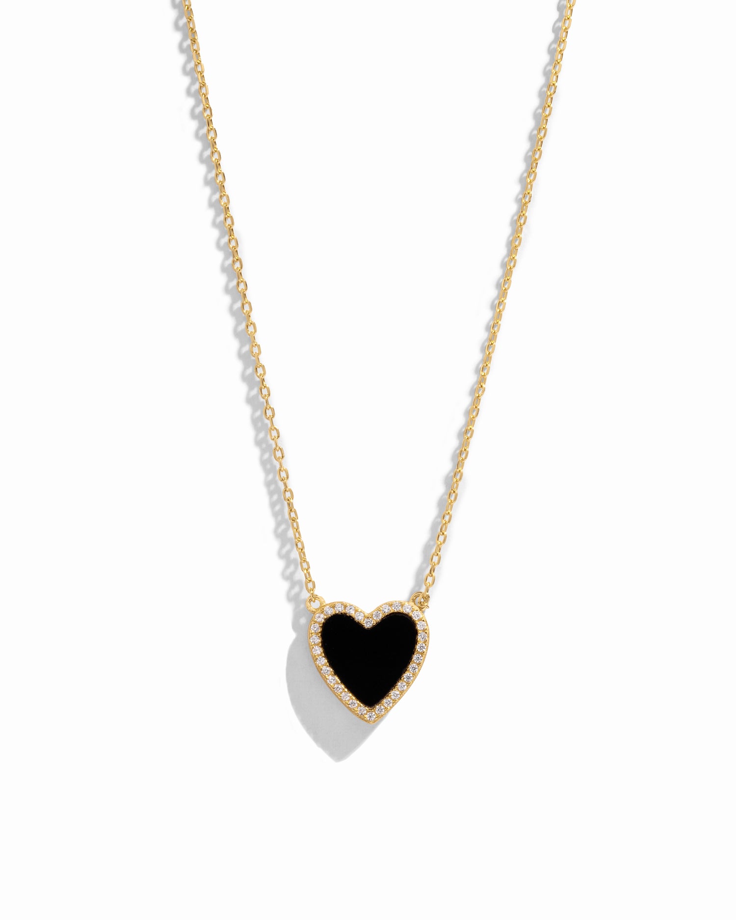 Close-up of a heart necklace with black onyx, set on a delicate gold chain 
