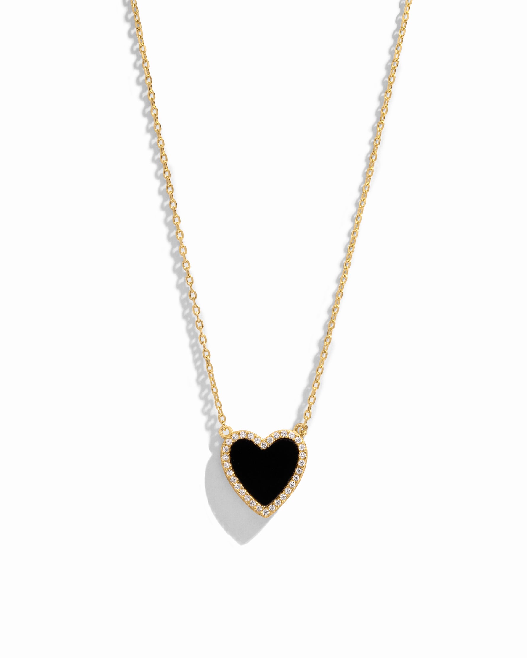 Close-up of a heart necklace with black onyx, set on a delicate gold chain 