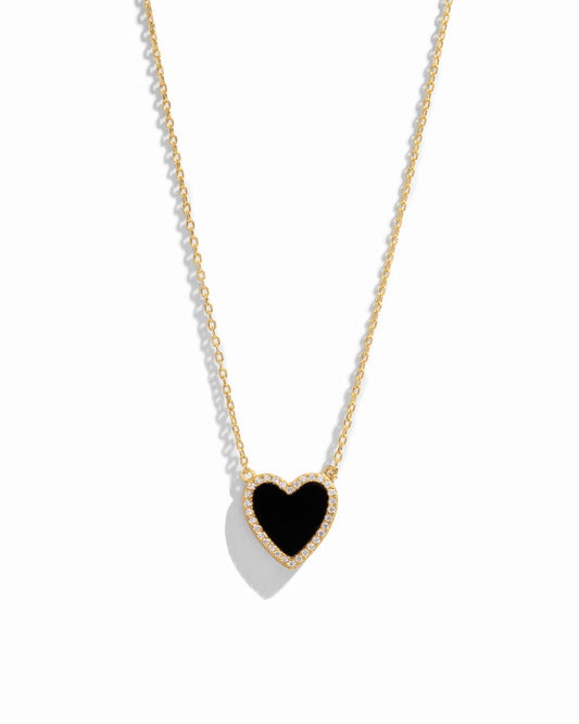 Close-up of a heart necklace with black onyx, set on a delicate gold chain 