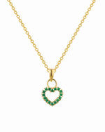 Gold necklace with a heart-shaped pendant featuring green gemstones on a white background