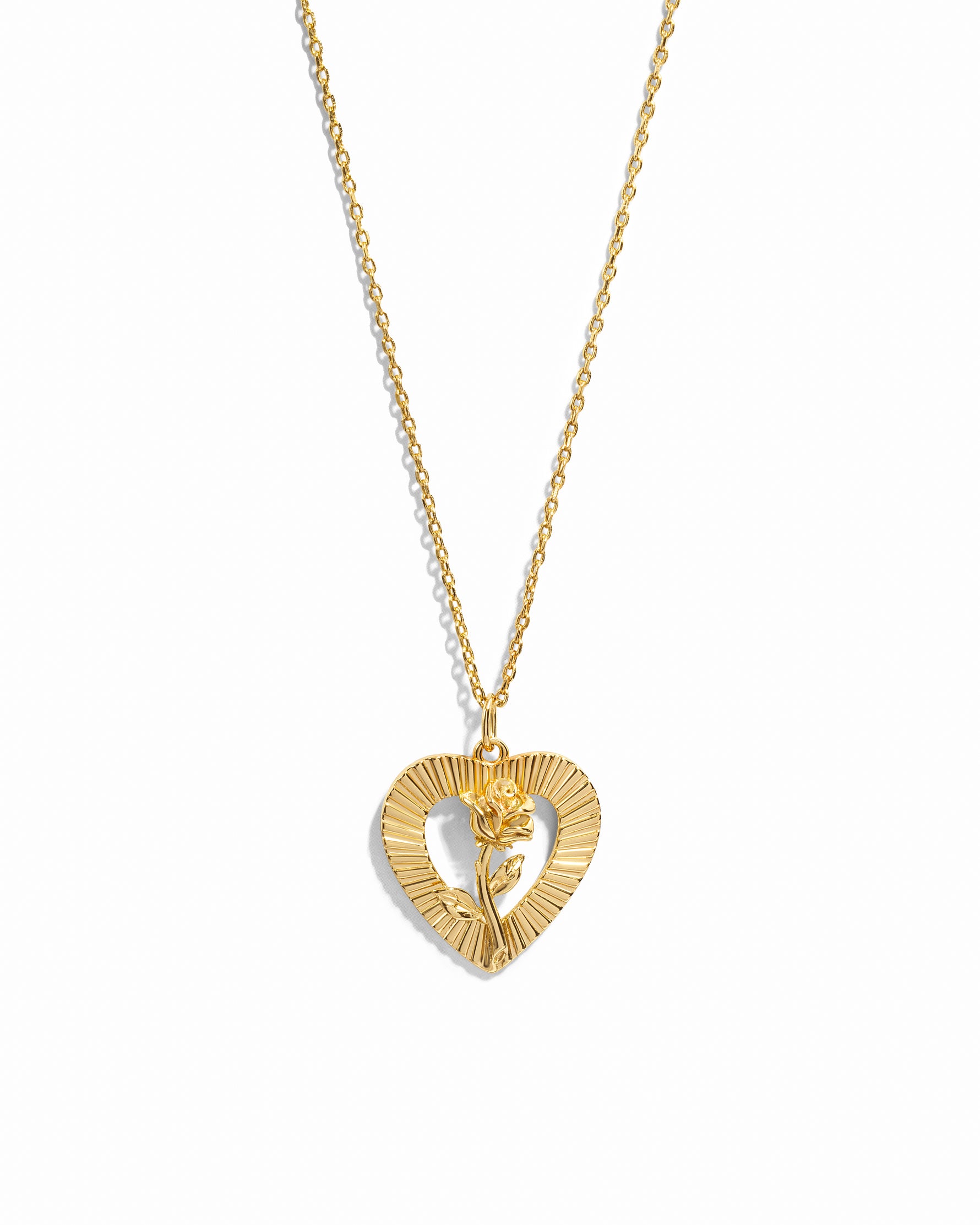 Gold rose necklace with heart pendant on white background
