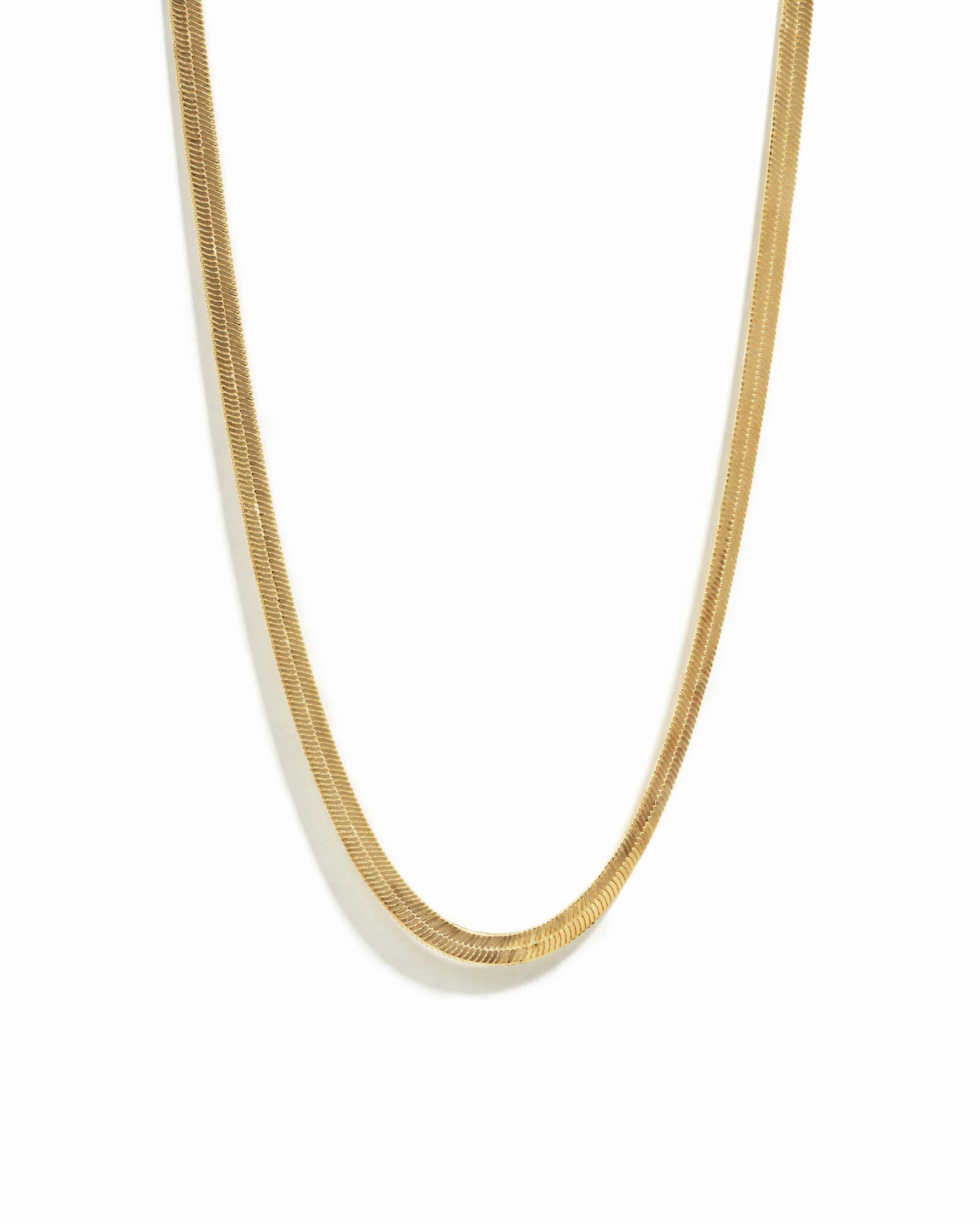 A gold 2mm herringbone chain necklace on a white background