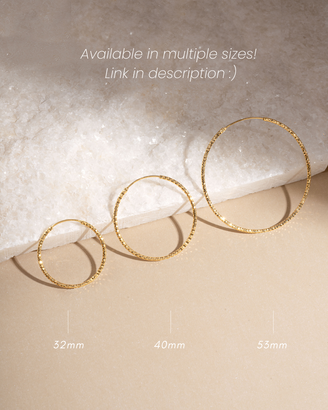 Three gold hoop earrings in different sizes on a textured surface with measurements indicated.