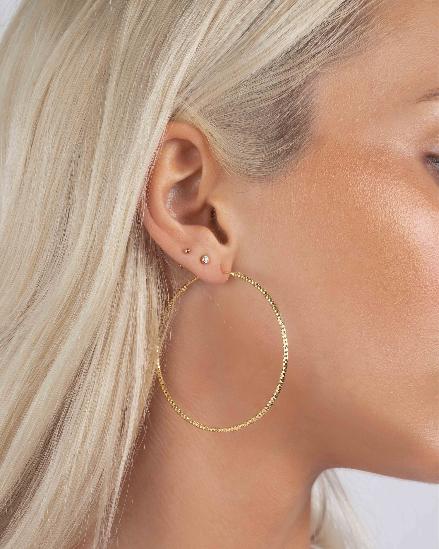 Model wearing 53mm diamond hoop earrings, bold yet lightweight earrings perfect as everyday gold hoops or statement earrings.