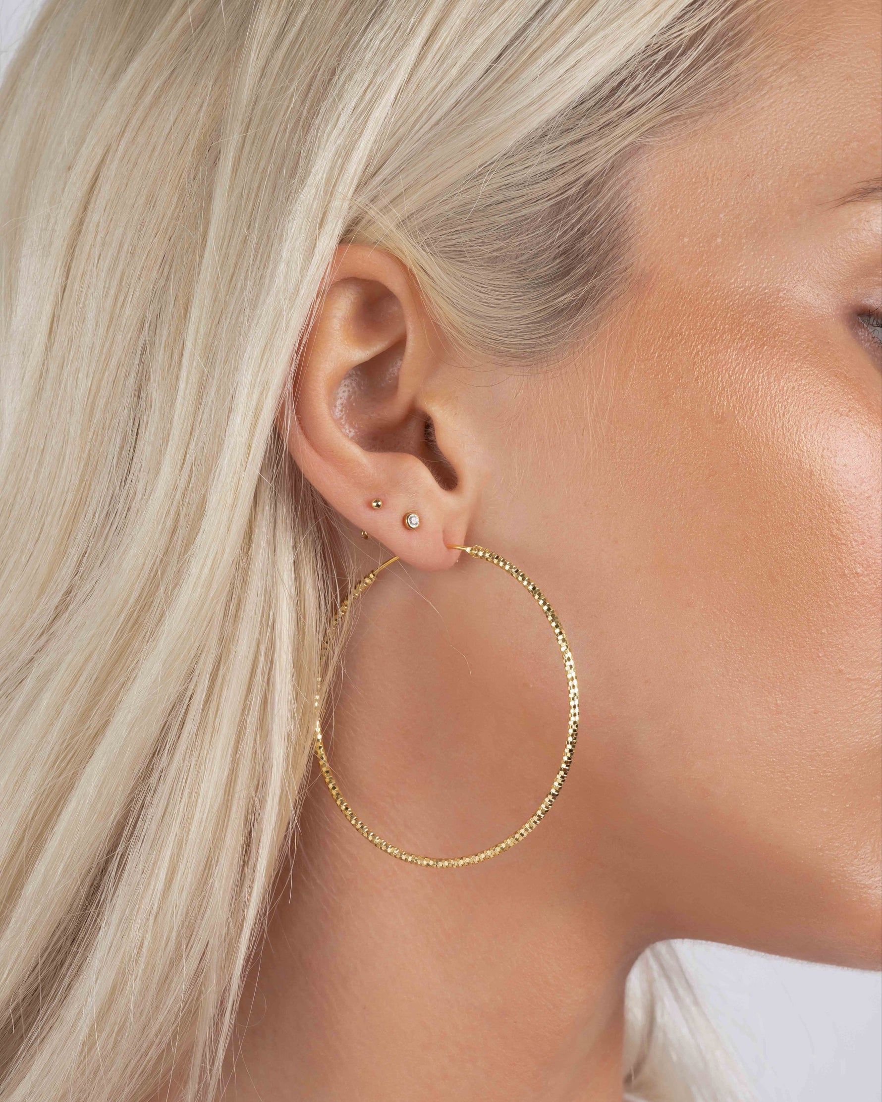 Model wearing 53mm diamond hoop earrings, bold yet lightweight earrings perfect as everyday gold hoops or statement earrings.