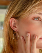 Model wearing 35mm gold textured hoop earrings with dainty bezel stud earrings, lightweight vintage-inspired hoops for everyday wear.