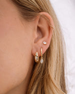 Model wearing tiny hoop earrings, dangle earrings, and a pear stud earring