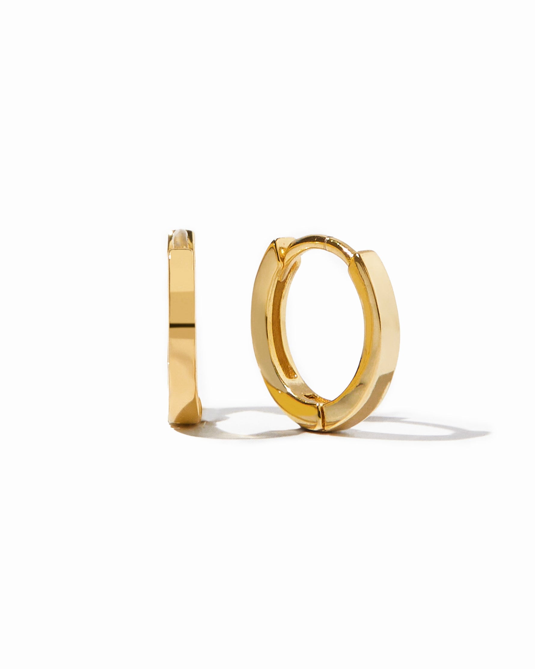 Gold huggie hoop earrings on a white background