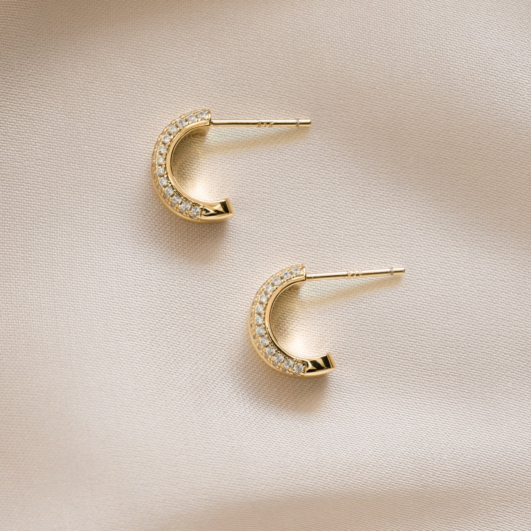 closeup image of gold double hoop earrings featuring  dainty cubic zirconia stones