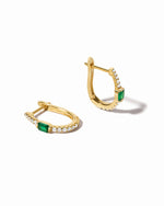 A pair of gold hoop earrings with emerald stones and diamond details, displayed against a white background.