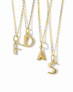 gold personalized jewelry, featuring different initial necklaces on a white background