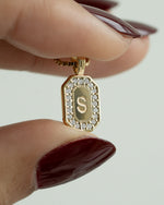 Gold personalized initial necklace with a pendant featuring the letter 'S' held between two fingers.