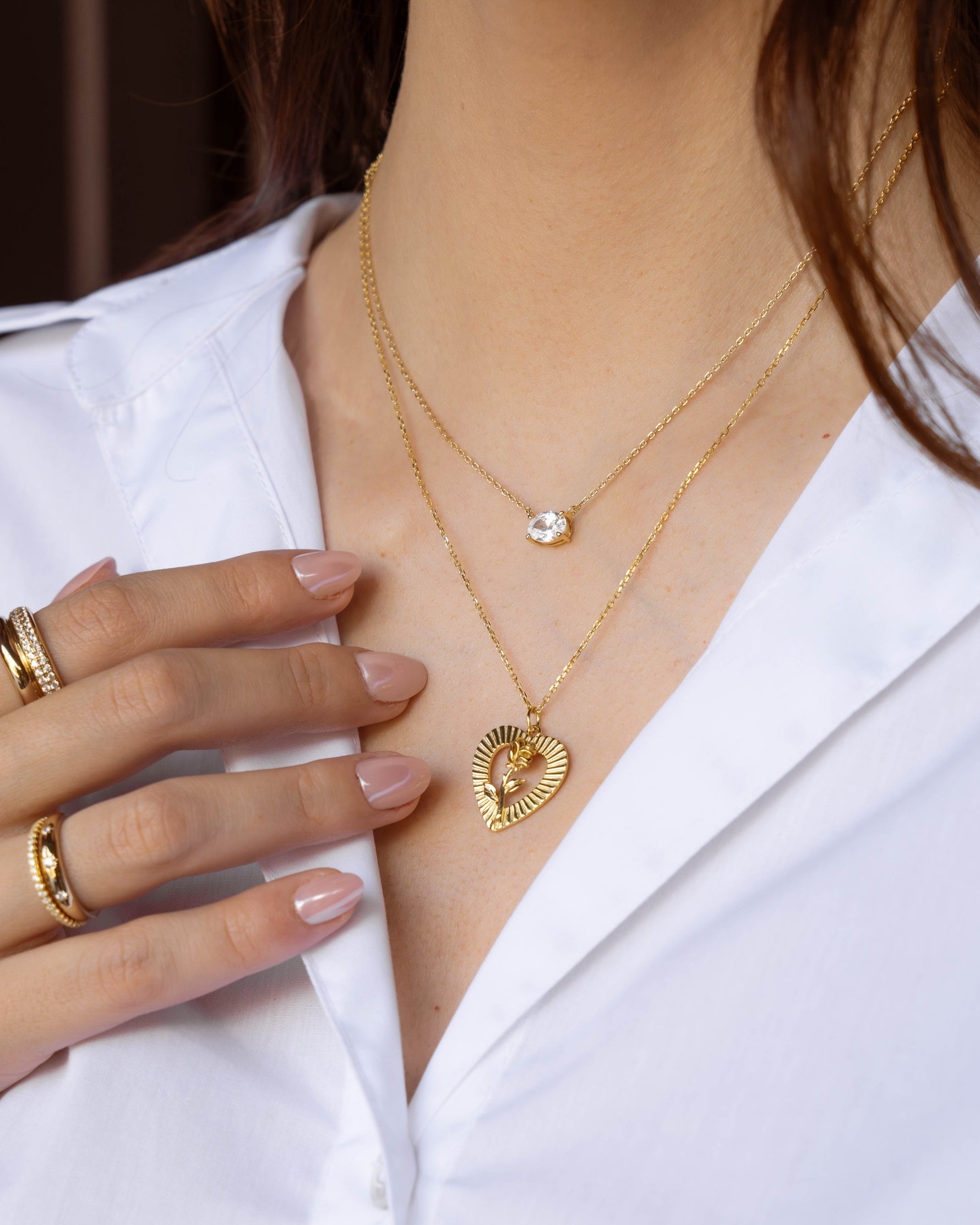 Model wearing gold vintage jewelry featuring a gold pendant statement necklace, a diamond necklace, and gold stackable rings
