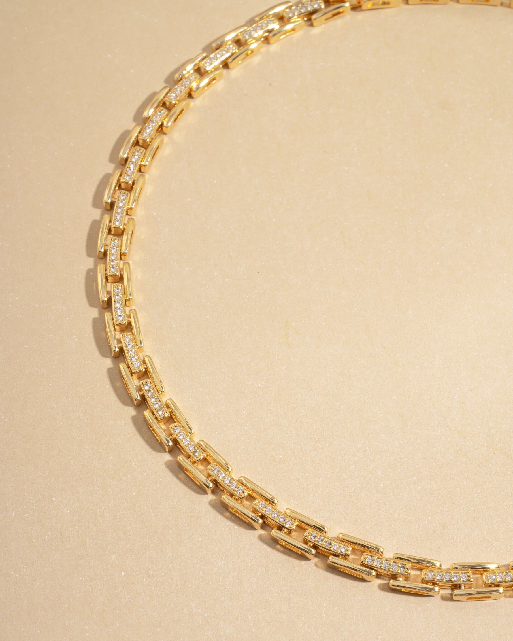 Gold statement jewelry featuring a choker necklace on a beige background