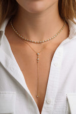 Gold layering necklaces featuring a diamond Y necklace and a tennis necklace