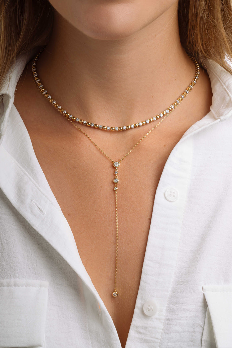 Gold layering necklaces featuring a diamond Y necklace and a tennis necklace