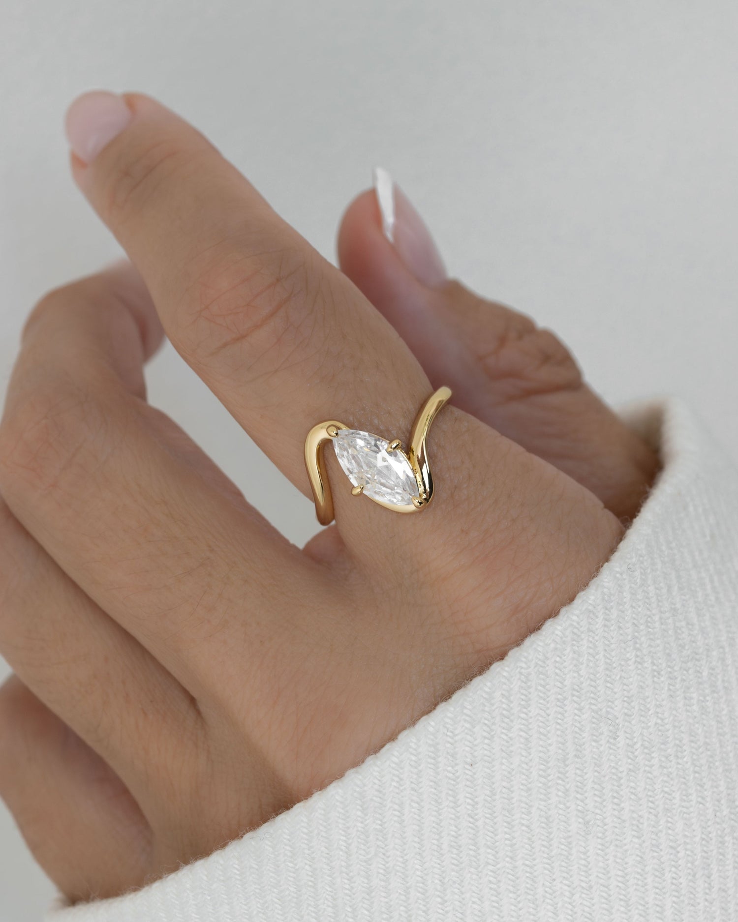 Gold statement ring with marquise diamond on models hand