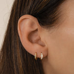 closeup image of dainty gold mini hoop earrings, paired with a simple huggie