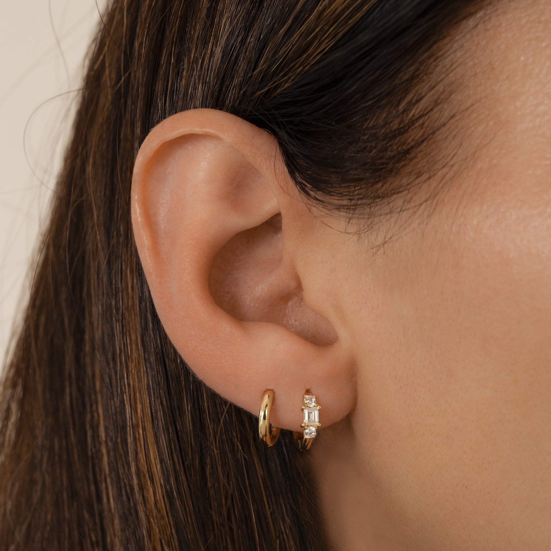 closeup image of dainty gold mini hoop earrings, paired with a simple huggie