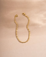 Gold chain bracelet on plain background