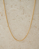 Gold chain minimalist necklace on beige background