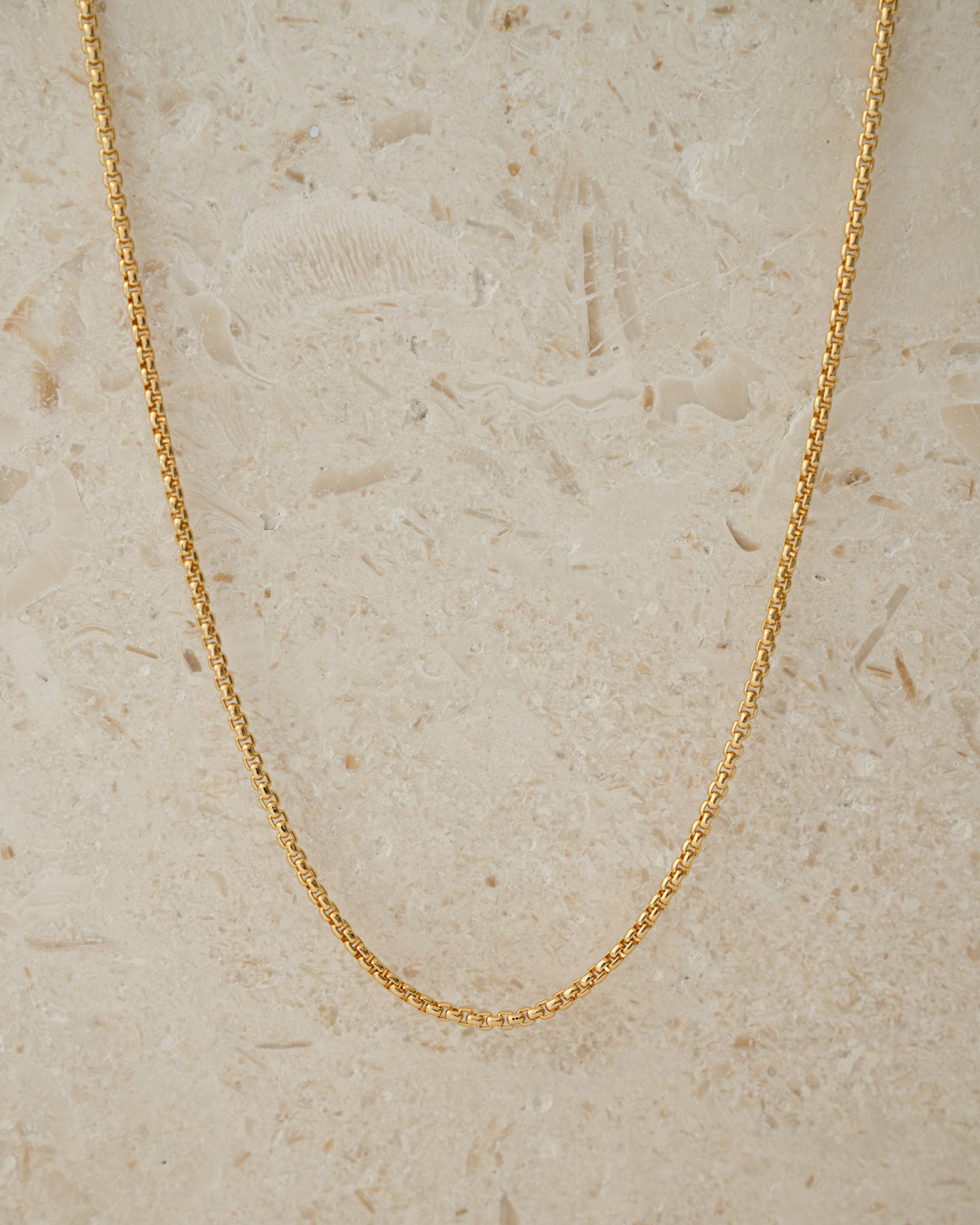 Gold chain minimalist necklace on beige background