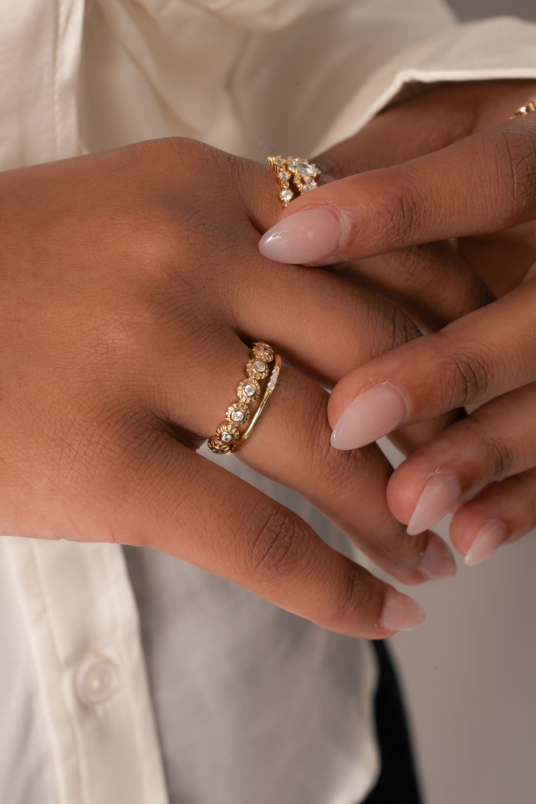 Closeup image of model wearing gold stacking rings including a dainty fluted diamond ring and a minimalist ring for stacking