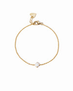 Gold bracelet with a small white opal stone on a white background