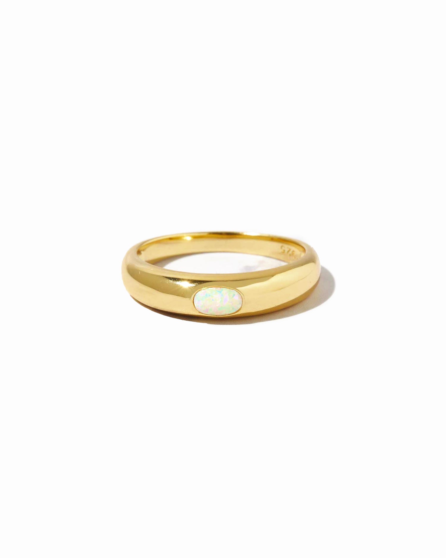 Gold ring with a central opal stone on a white background